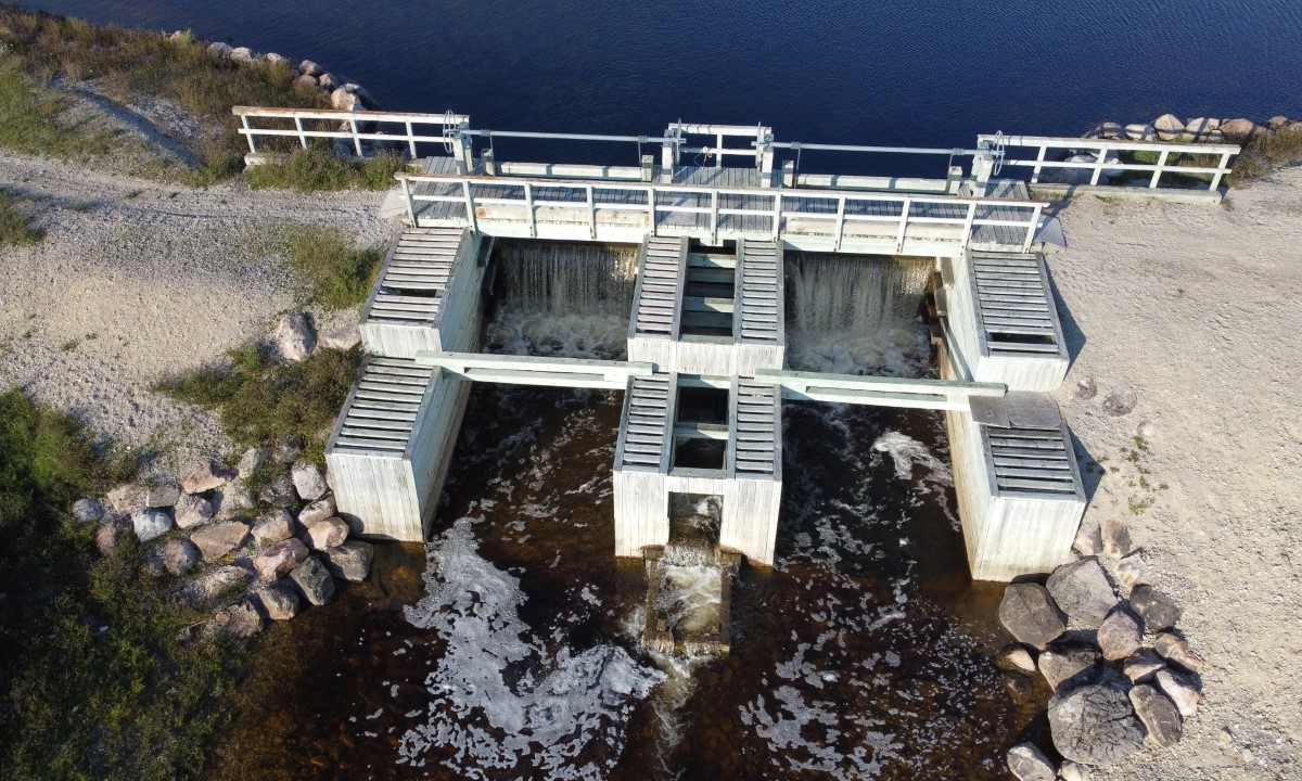 Vue aérienne d’un barrage retenant un plan d’eau entouré de forêt et d’un chemin d’accès à Sept-Îles